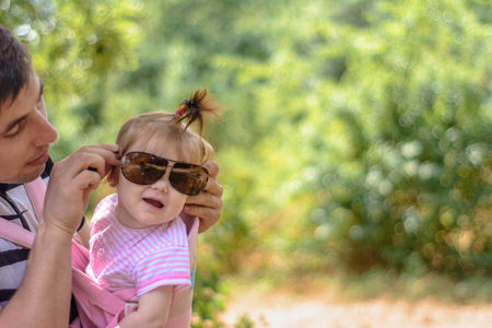 Little wonder girl in a pink dress and sunglasses is playing with her young fatherの写真素材