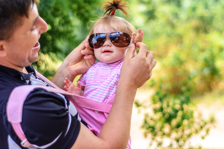 Little wonder girl in a pink dress and sunglasses is playing with her young fatherの写真素材