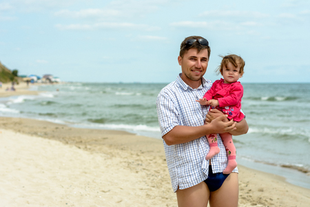 Young father in sunglasses on the beach with a little daughterの写真素材