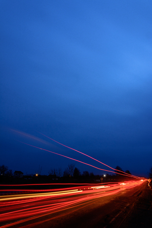 Photos of Ukrainian roads under the evening sky, on which cars are moving and blurring the way with their lightの写真素材