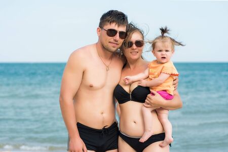 Young parents are holding a small daughter on the back of the sea and the sky 2018の写真素材