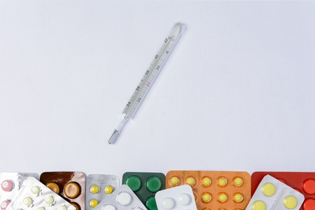 Photometer of a thermometer on a white background among tablets of different colors in packages of...