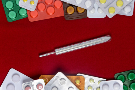 Packages of tablets are located on a red background with a place for the inscriptionの写真素材