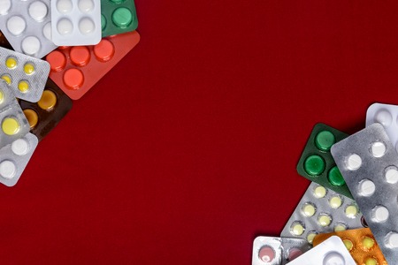 Packages of tablets are located on a red background with a place for the inscriptionの写真素材