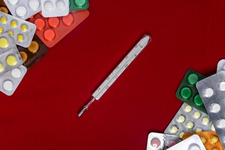 Packages of tablets are located on a red background with a place for the inscriptionの写真素材