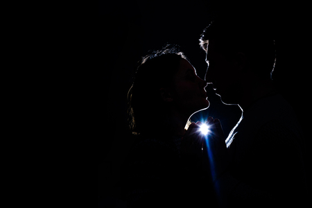 A pair of lovers is in the dark, through which the rays break through and illuminate their silhouetteの写真素材