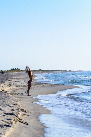 Young beautiful girl perform exercises on gymnastics on the shores of the black seaの写真素材