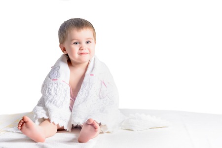A charming little girl wrapped in a white scarf sitting on a white background 2018の写真素材