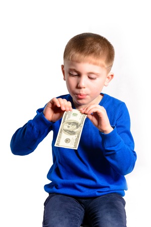 A little boy in a blue jacket holds a hundred dollars, isolated on a white backgroundの写真素材