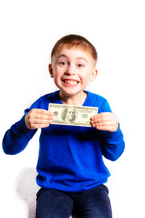 A little boy in a blue jacket holds a hundred dollars, isolated on a white backgroundの写真素材