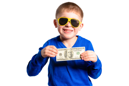 A little boy in a blue jacket holds a hundred dollars, isolated on a white backgroundの写真素材