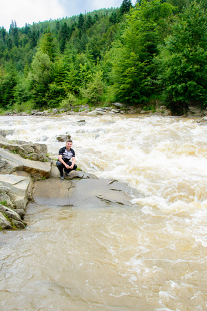 Young man against the background of a mountain river in the Ukrainian Carpathians 2018の写真素材