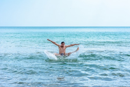 A sports man jumping over the sea waves in the black sea 2018
