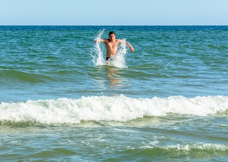 A sports man quickly runs from the beach in the sea waves 2018の写真素材