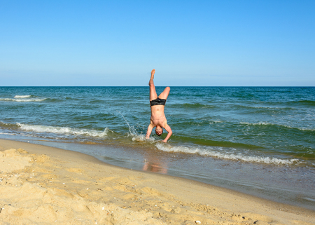 A sports man walks up the beach in the sea waves 2018の写真素材