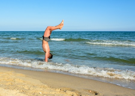 A sports man walks up the beach in the sea waves 2018の写真素材