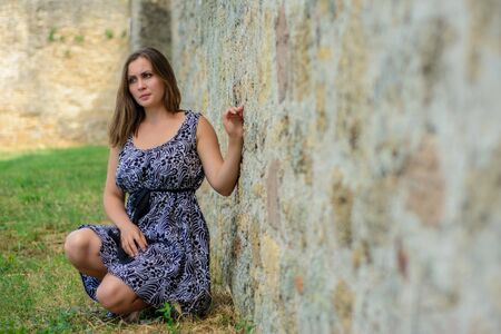 Beautiful girl in a dress sitting on the backgroundの写真素材