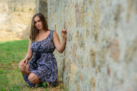 Beautiful girl in a dress sitting on the backgroundの写真素材