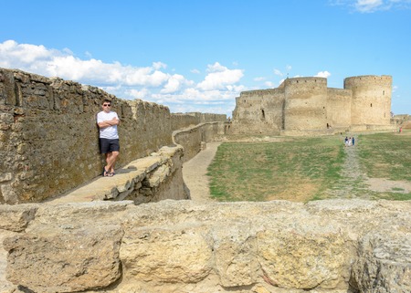 A young man in a white T-shirt and sunglasses stands on the wallの写真素材