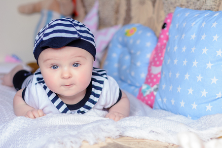 A beautiful little boy in a costume sailor lays on a bed near the pillows 2018の写真素材