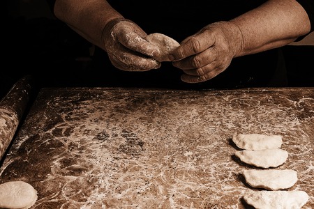 The hands of an old grandmother mold vareniks on a dark background 2018の写真素材