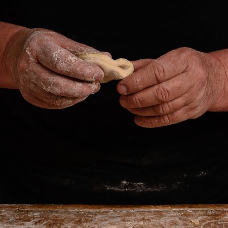 The hands of an old grandmother mold vareniks on a dark background 2018の写真素材