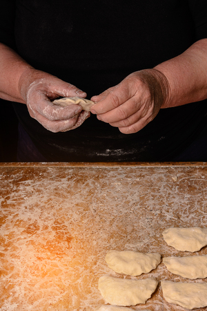 The hands of an old grandmother mold vareniks on a dark background 2018の写真素材