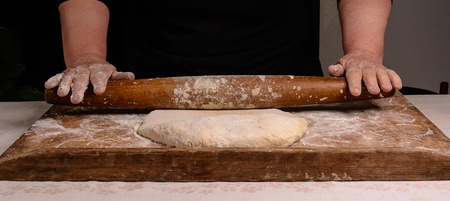 An old grandmother cleansing a dough with a shaft on a dark background 2018