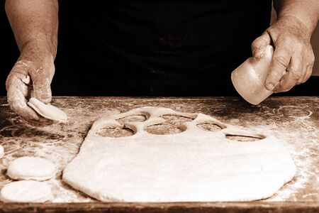 Granny squeezes a glass of a circle in a dough on the table 2018の写真素材
