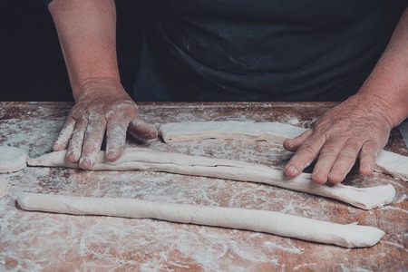An elderly woman rolls out of a raw batter for baking on a dark background 2018の写真素材