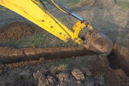 A work excavator digs a trench in a country houseの写真素材