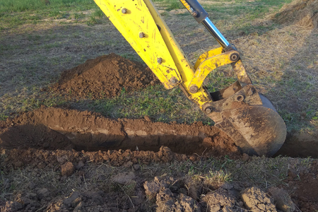 A work excavator digs a trench in a country houseの写真素材