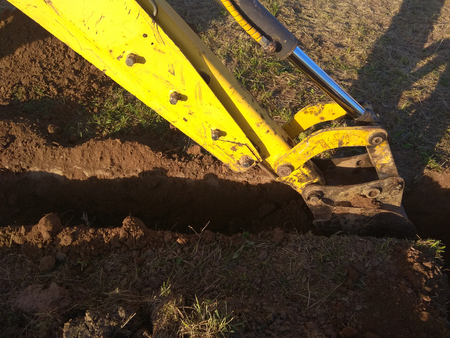 A work excavator digs a trench in a country houseの写真素材