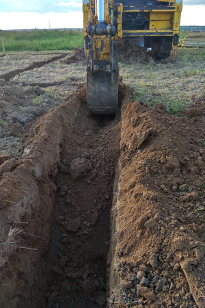 View from above at working excavator tractor digging a trench.の写真素材
