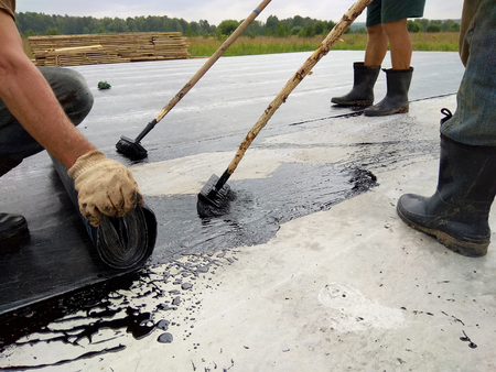 Roofer worker painting bitumen praimer at concrete surface by the roller brush Waterproofingの写真素材