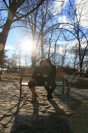 Beautiful happy young couple sitting on the bench in sunny park and making heart gesture together 2018の写真素材