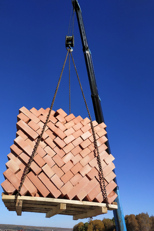 The car crane transfers the brick to the construction site on the background of the sky and field 2018の写真素材