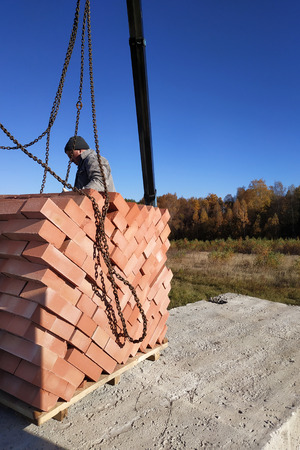 The car crane transfers the brick to the construction site on the background of the sky and field 2018の写真素材