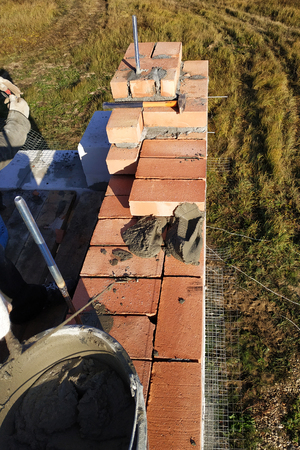the worker puts the brick on the cement mortar on the background of the grass 2018の写真素材