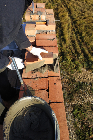 the worker puts the brick on the cement mortar on the background of the grass 2018の写真素材
