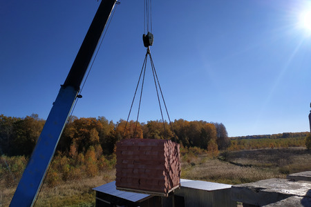 The car crane holds and unloads the brick on the background of the blue autumn sky 2018の写真素材