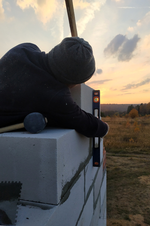 The master uses a rubberized hammer to level the blocks during the construction of the wall 2018の写真素材