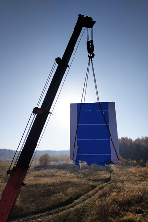 A truck crane raises white blocks to the construction site against the background of the sun shining 2018の写真素材