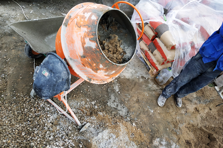 auxiliary worker uses a shovel to prepare a cement mortar on a construction siteの写真素材