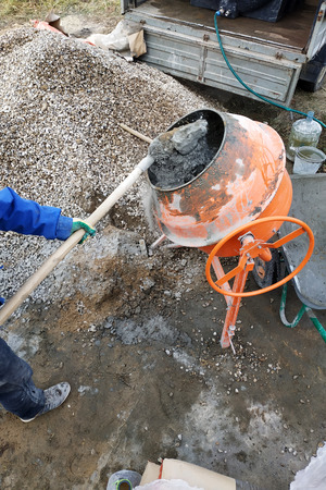 auxiliary worker uses a shovel to prepare a cement mortar on a construction siteの写真素材