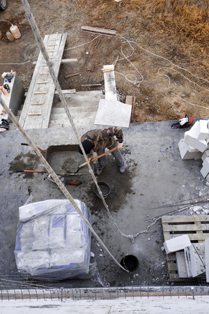 The worker collects a cement mortar in a carriage bucket on the construction siteの写真素材