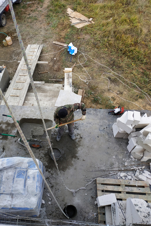 The worker collects a cement mortar in a carriage bucket on the construction siteの写真素材
