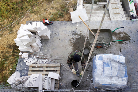 The worker collects a cement mortar in a carriage bucket on the construction siteの写真素材