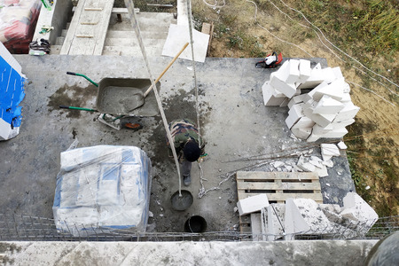 The worker collects a cement mortar in a carriage bucket on the construction site