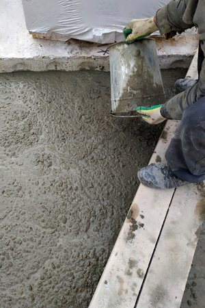 The builder pours a cement mortar slab between the floors of the house using a bucketの写真素材